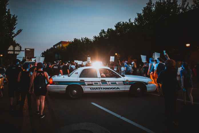 cop car surrounded by group of people on meeting