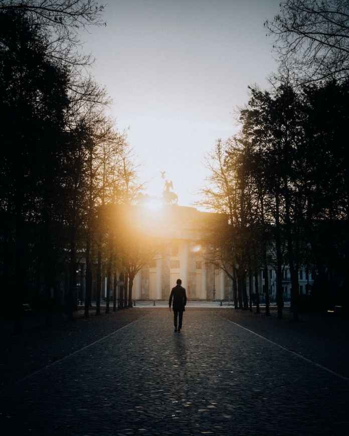 silhouette of a man walking in the alley toward the brandenburg gate in berlin germany
