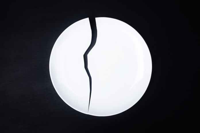 broken white ceramic plate on black background