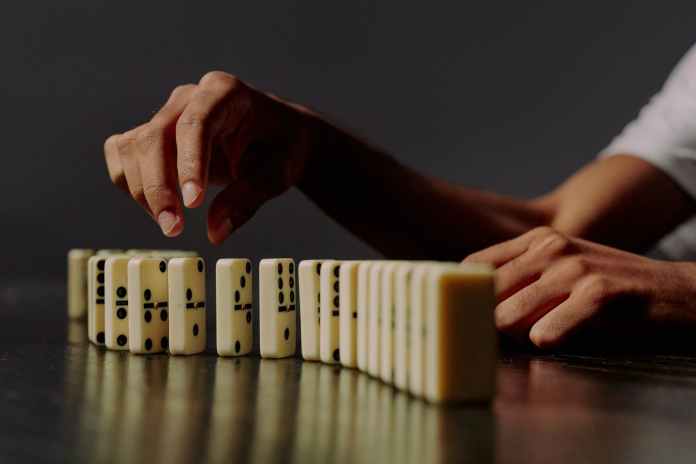 domino blocks in a row and human hand trying to take one of it