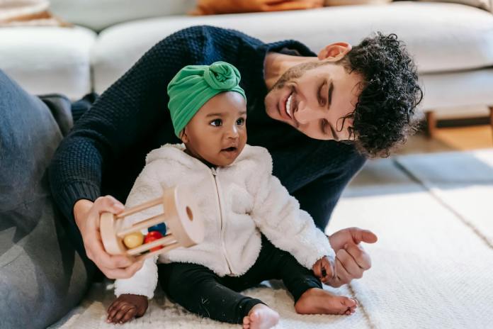 smiling father playing with indian baby girl at home